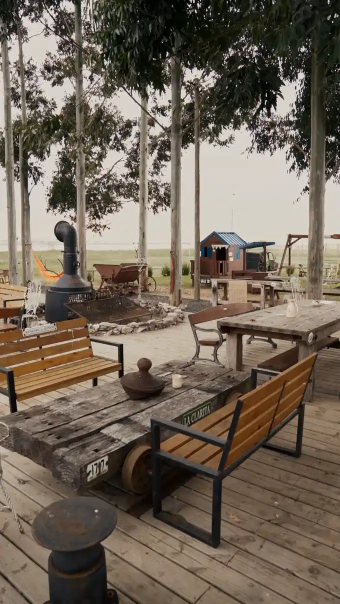 Barbacoa con parrilla y fuego encendido, mesa larga y vista al campo