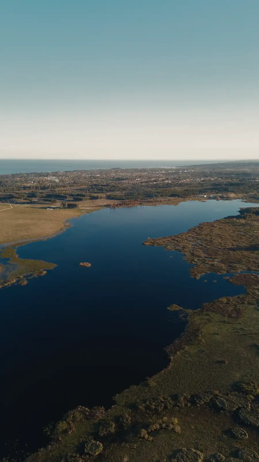 Vista aérea de la Laguna del Cisne con la costa de juncos y el campo alrededor
