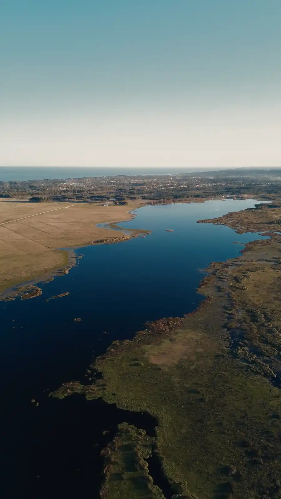La laguna vista desde el aire, con la franja de reserva natural entre el agua y el campo